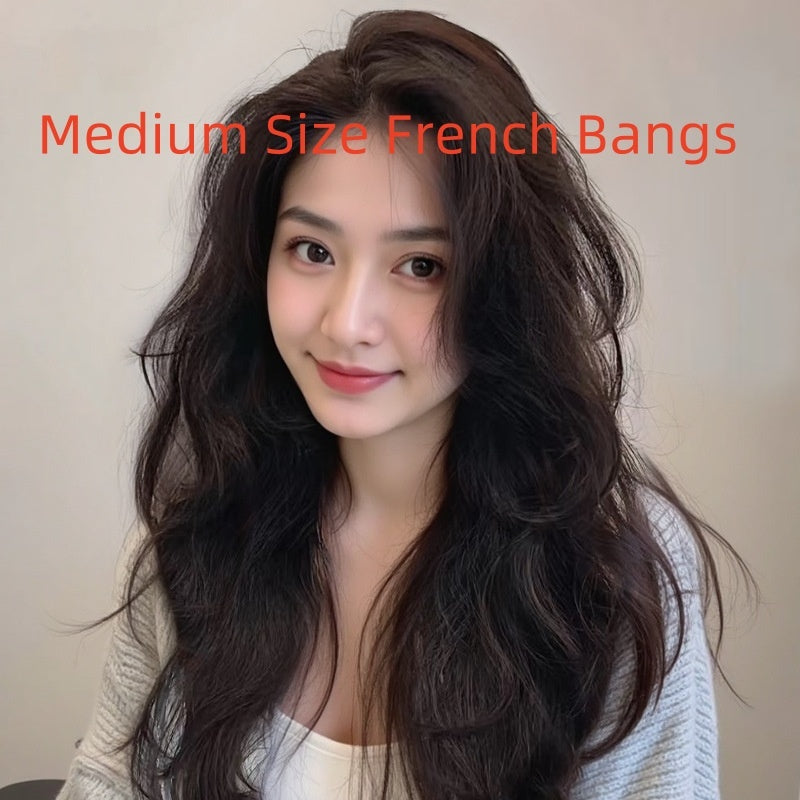 Model showcasing medium-sized French bangs with long, wavy hair in natural tones.