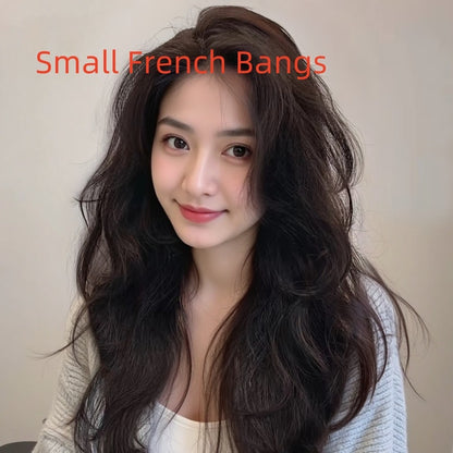 Model showcasing a small French bangs hairstyle with long curly hair in natural dark tones.
